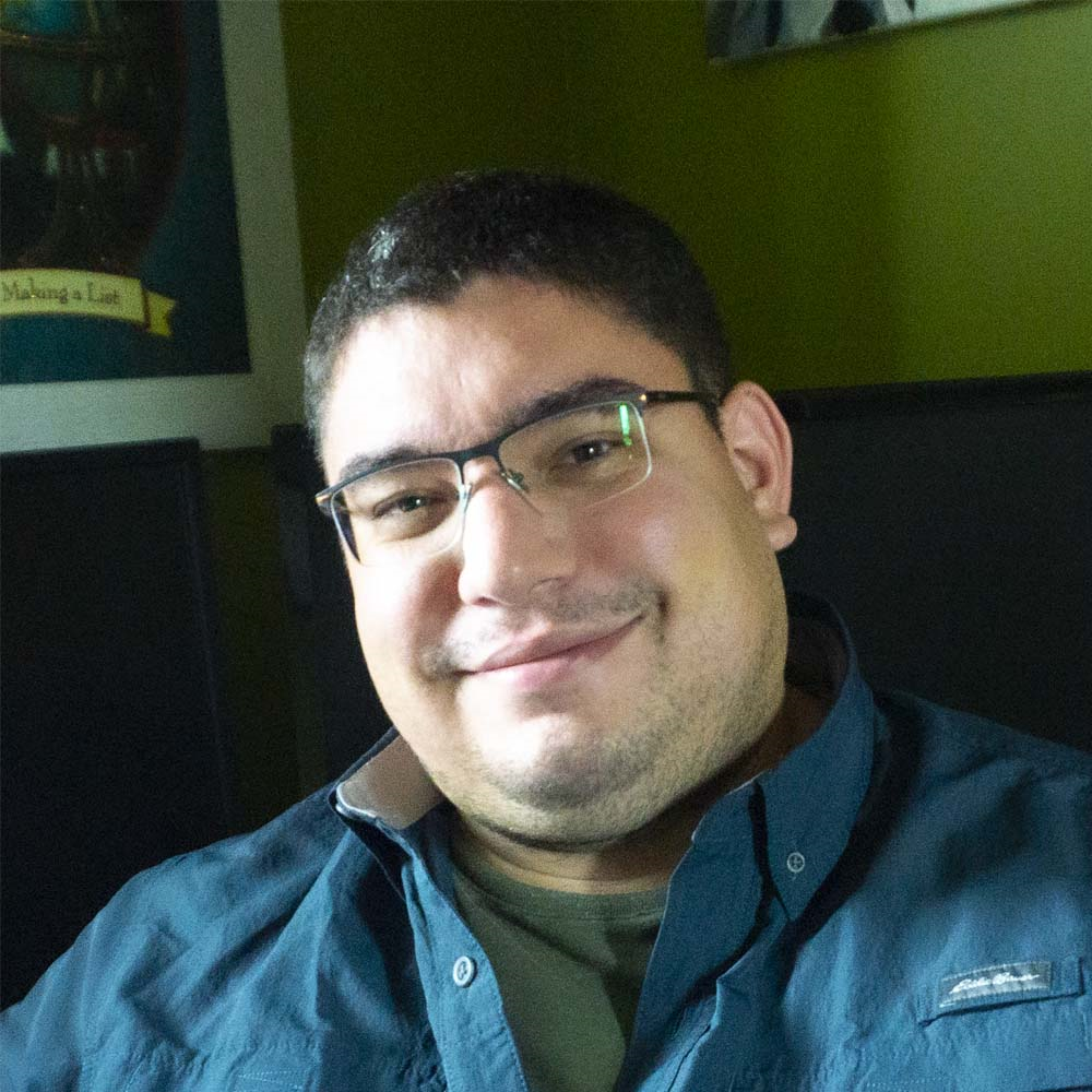 picture of Chris Kovacs sitting at his desk with the computer behind him.